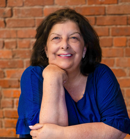 Dr. Elena Mazza,  dark haired woman wearing a blue top